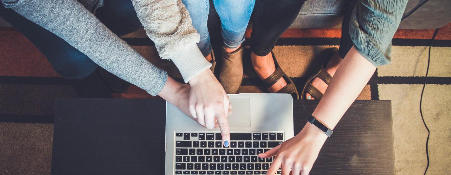 Vier Personen deuten auf einen Laptop