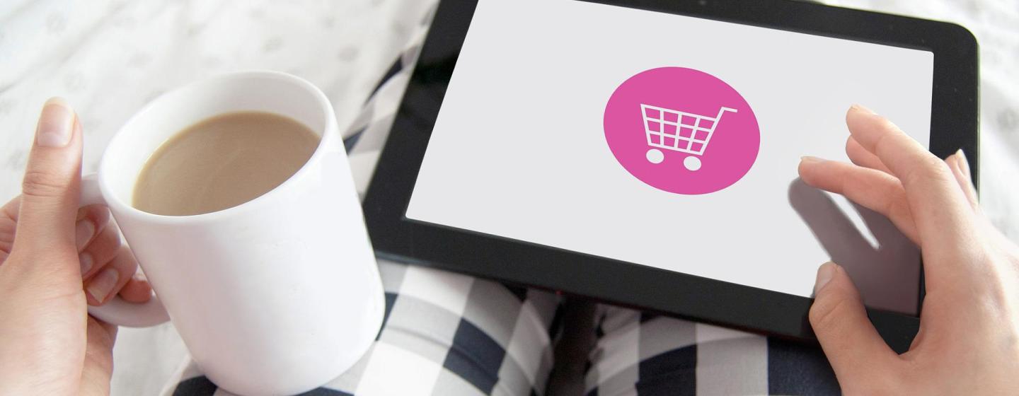 Bild einer Person, die im Pyjama mit Kaffeetasse in der Hand am Tablet online einkauft. Credit von Pixabay.