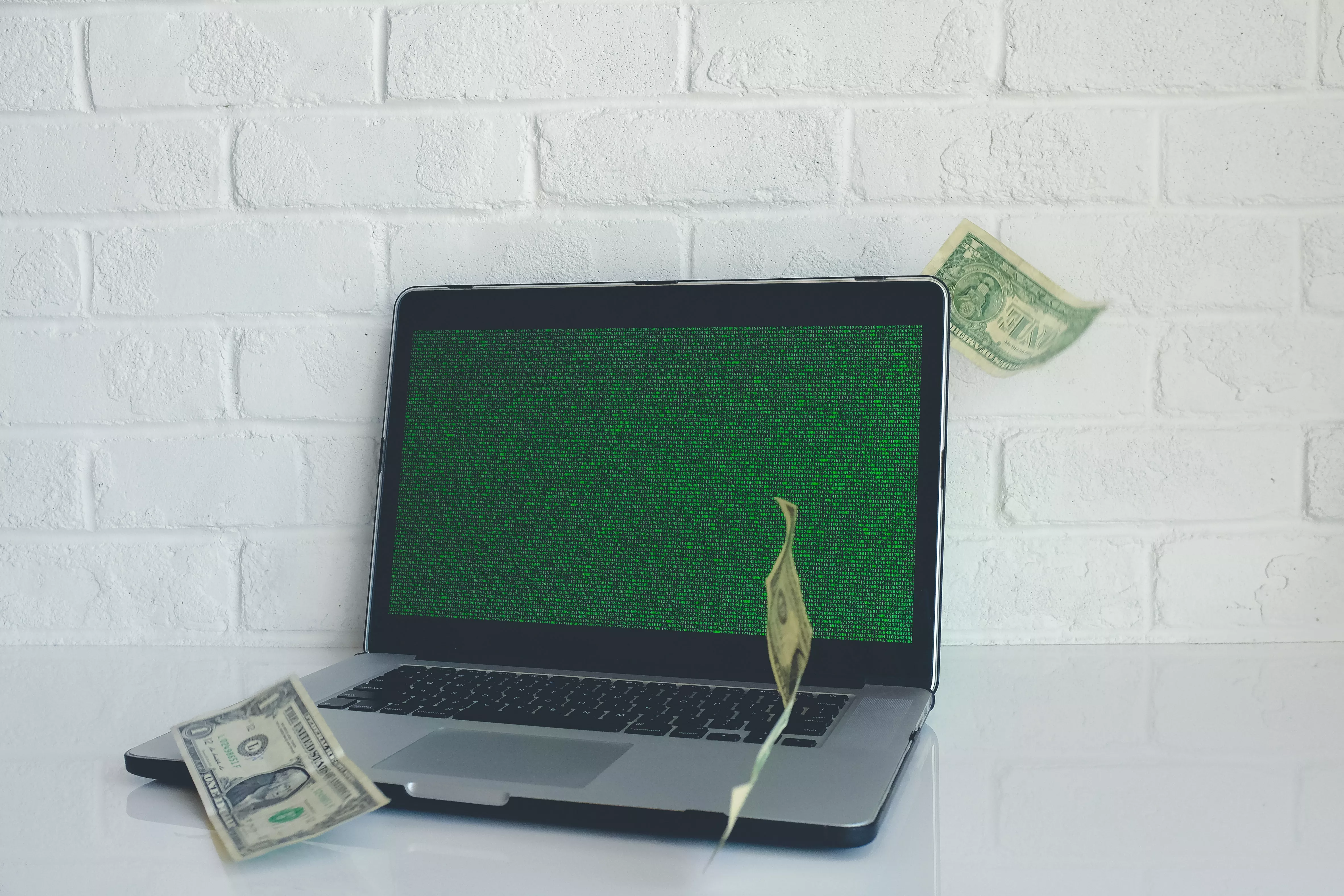 Ein Laptop mit Code und Geldscheinen