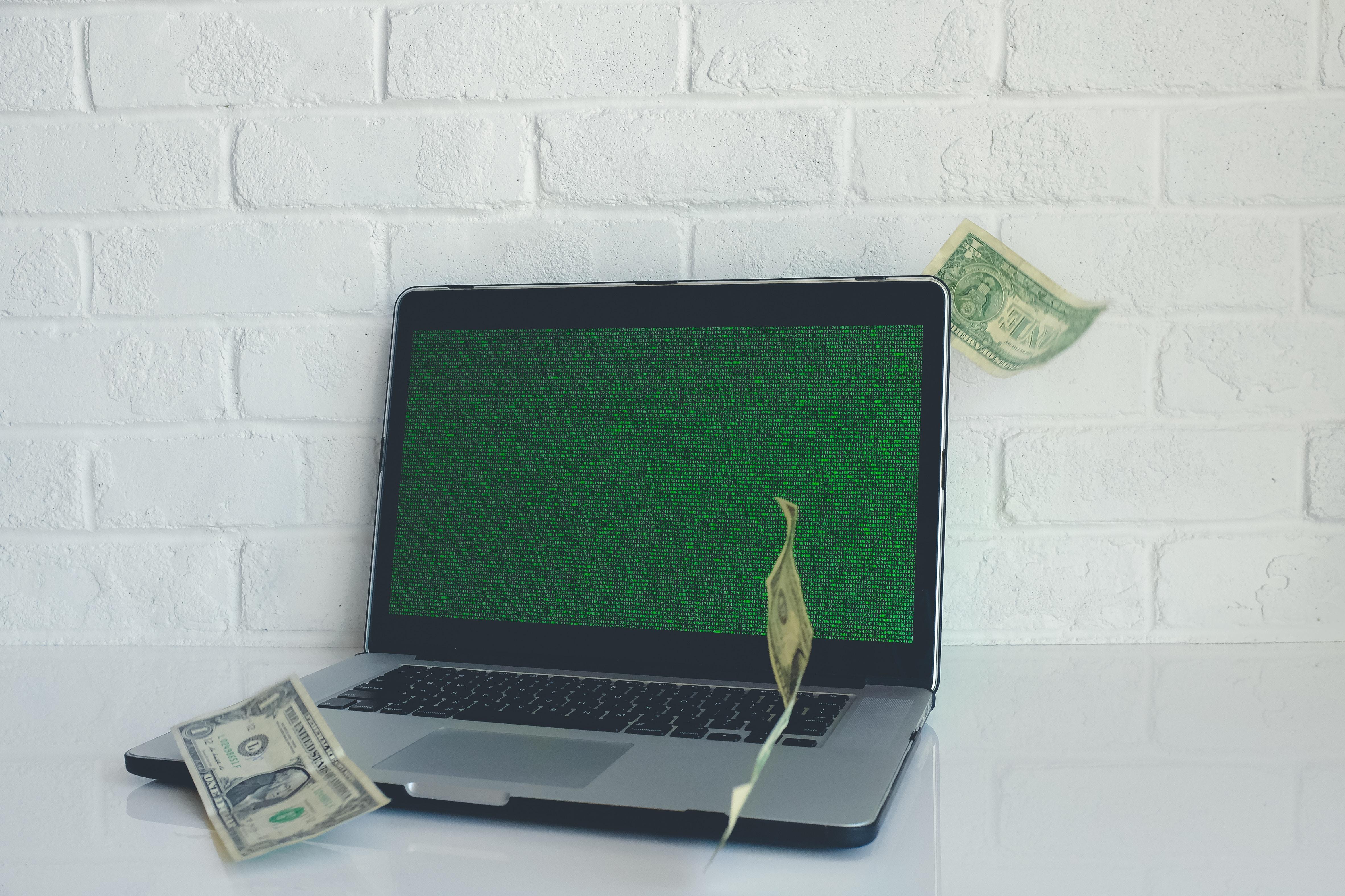 Ein Laptop mit Code und Geldscheinen