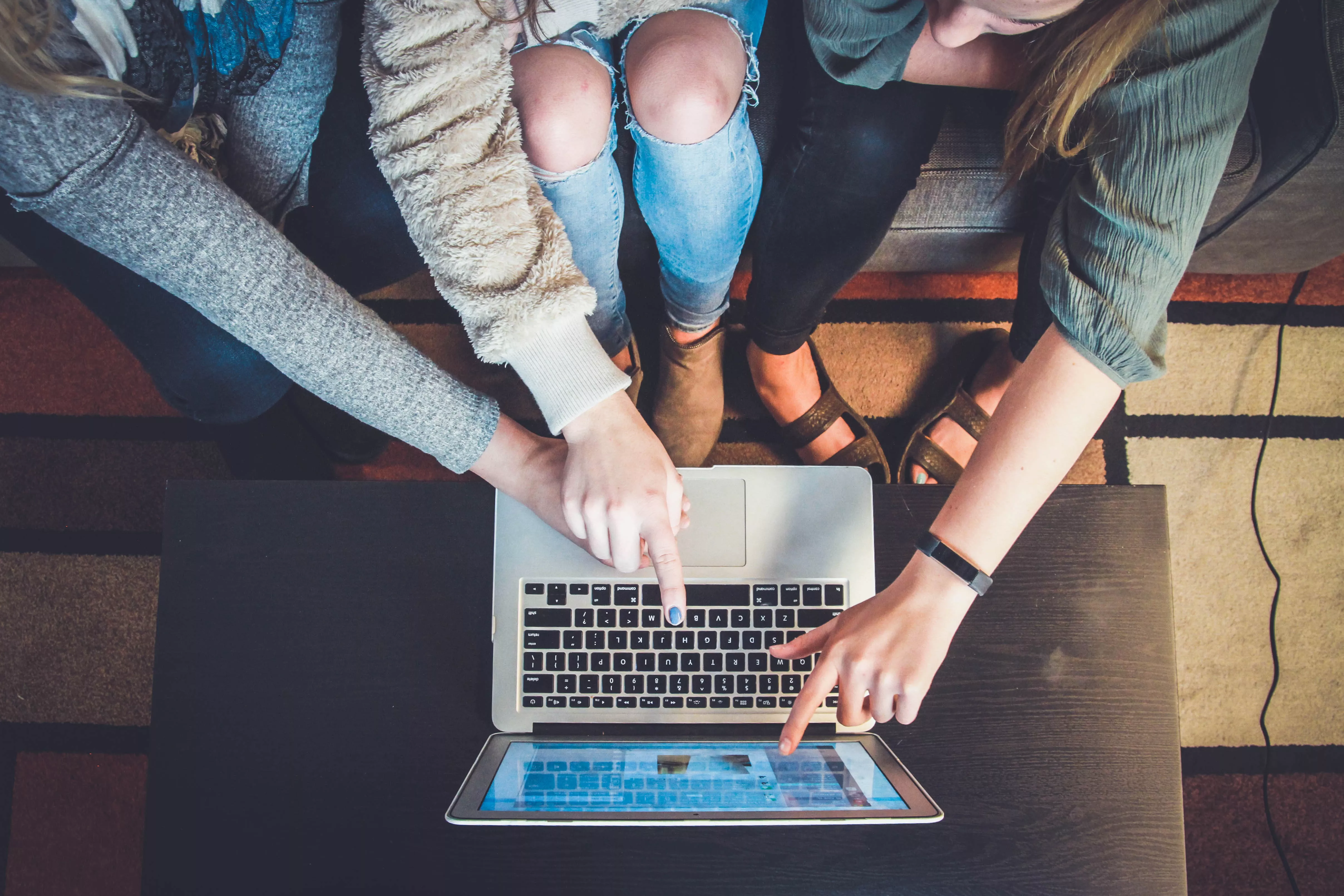 Vier Personen deuten auf einen Laptop