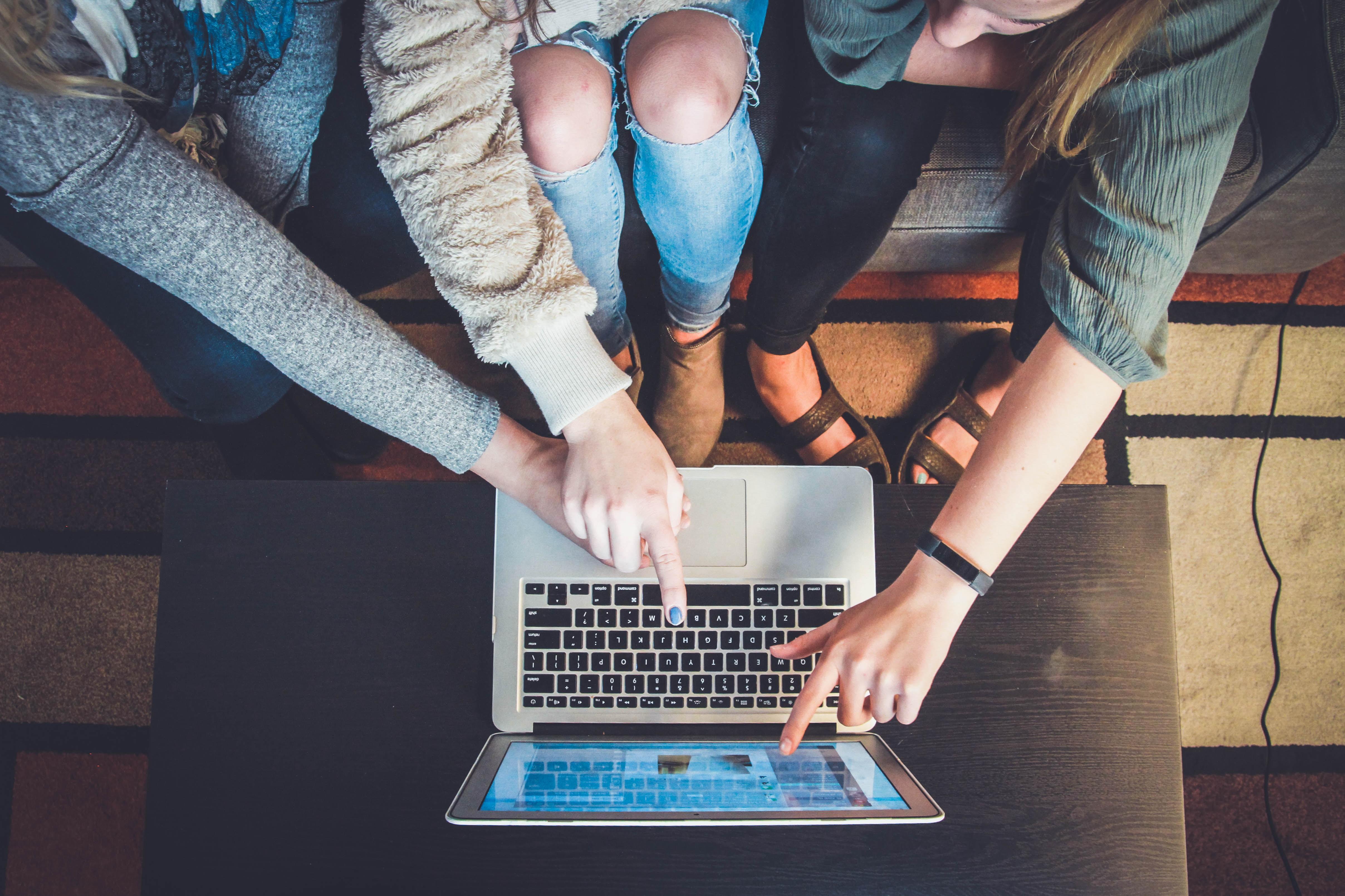 Vier Personen deuten auf einen Laptop