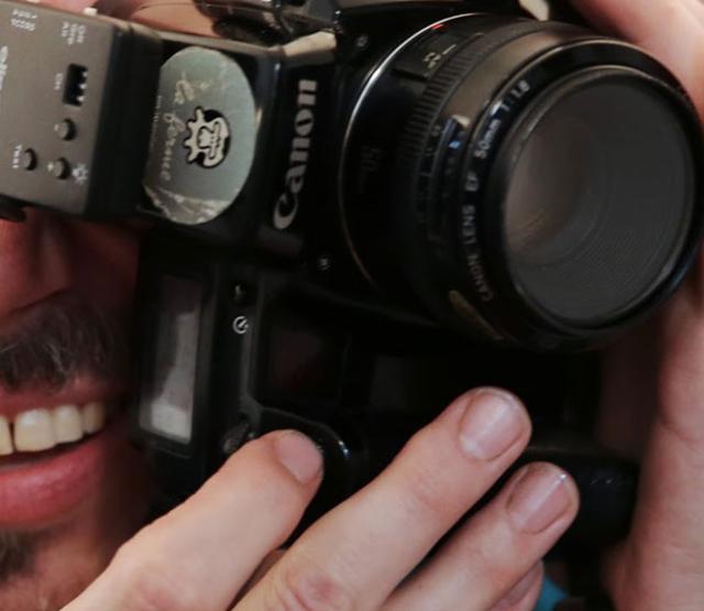 Portraitfoto von Christoph Uiberacker mit Fotoapparat vor Gesicht