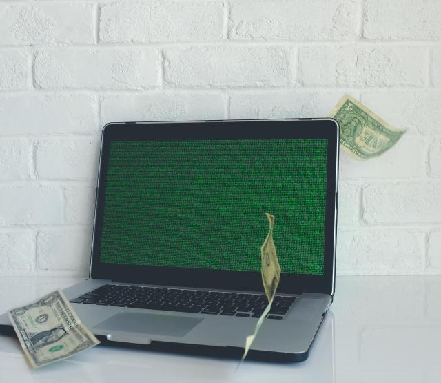 Ein Laptop mit Code und Geldscheinen
