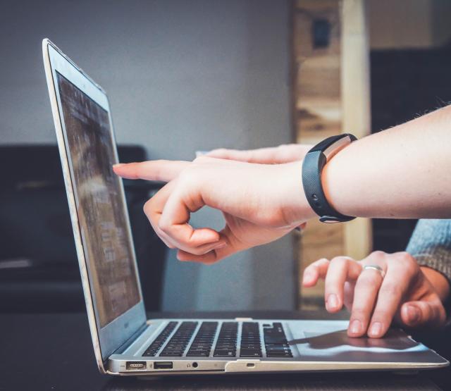 Eine Person deutet auf einen Laptop