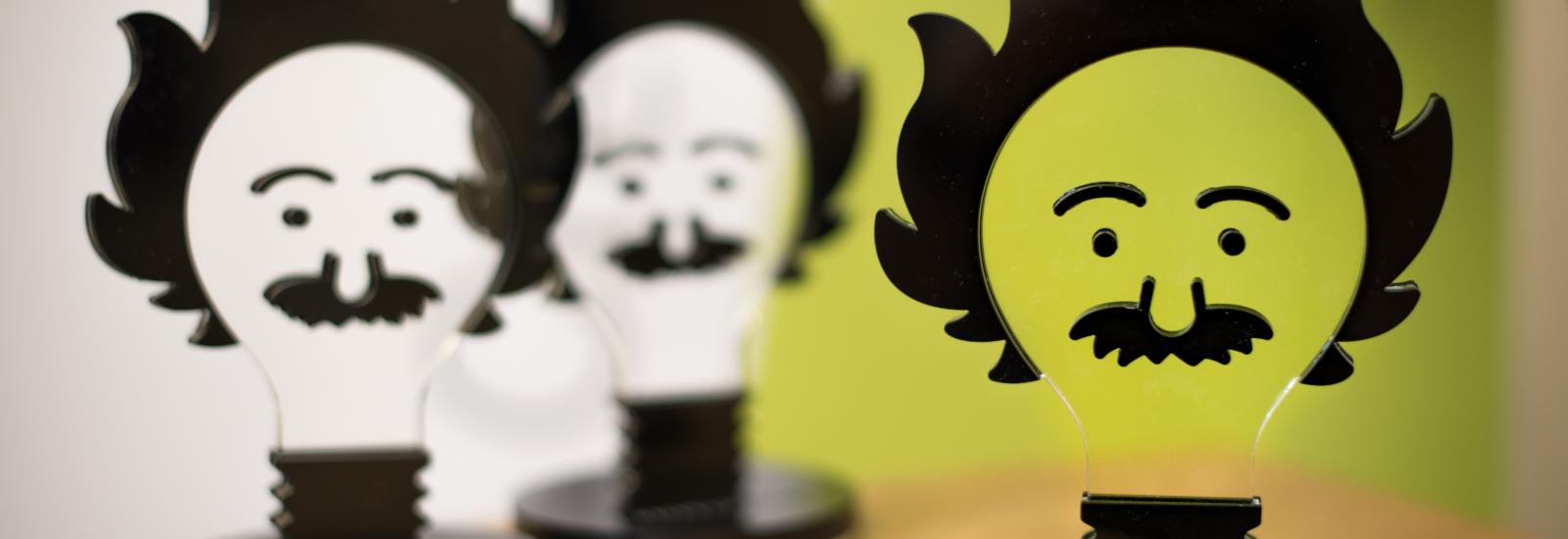 3 Awards nebeneinander in der form einer Glühbirne, die aussieht wie Albert Einstein