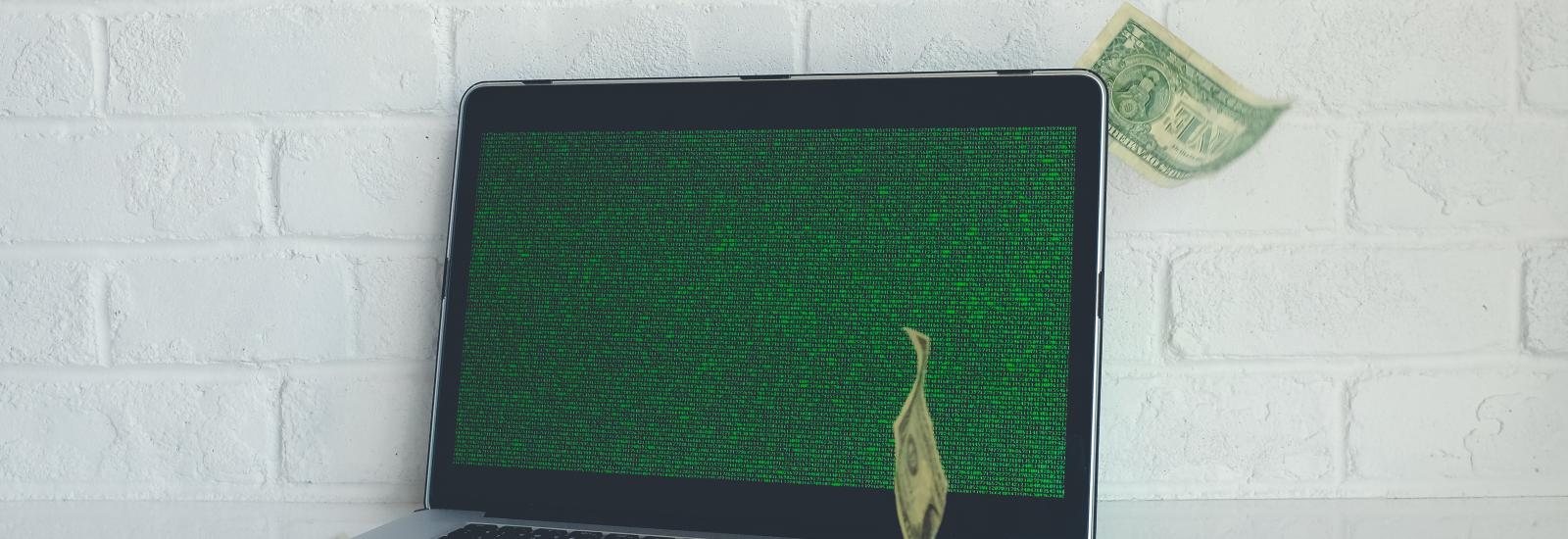 Ein Laptop mit Code und Geldscheinen