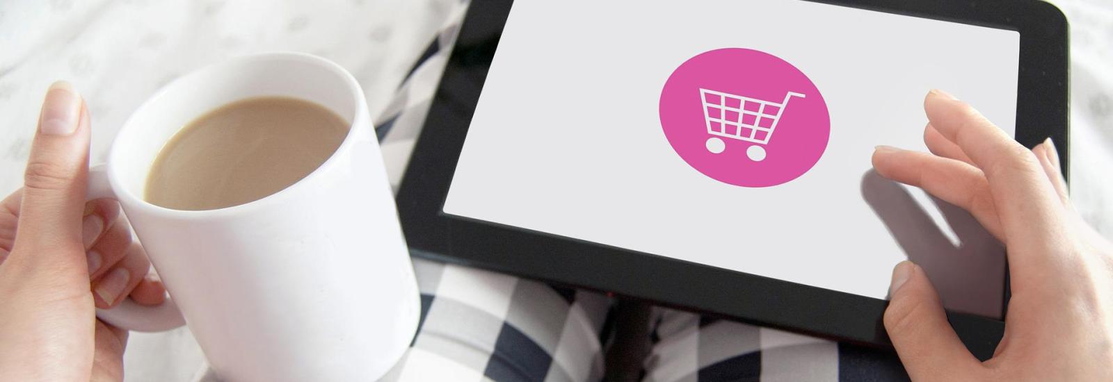 Bild einer Person, die im Pyjama mit Kaffeetasse in der Hand am Tablet online einkauft. Credit von Pixabay.