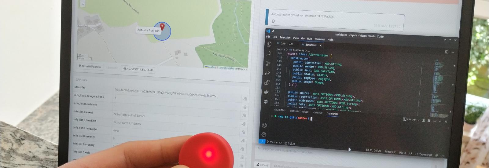 Laptop mit laufendem DEC112 Viewer. Im Vordergrund eine Hand mit einem Puck.js, welcher rot leuchtet.