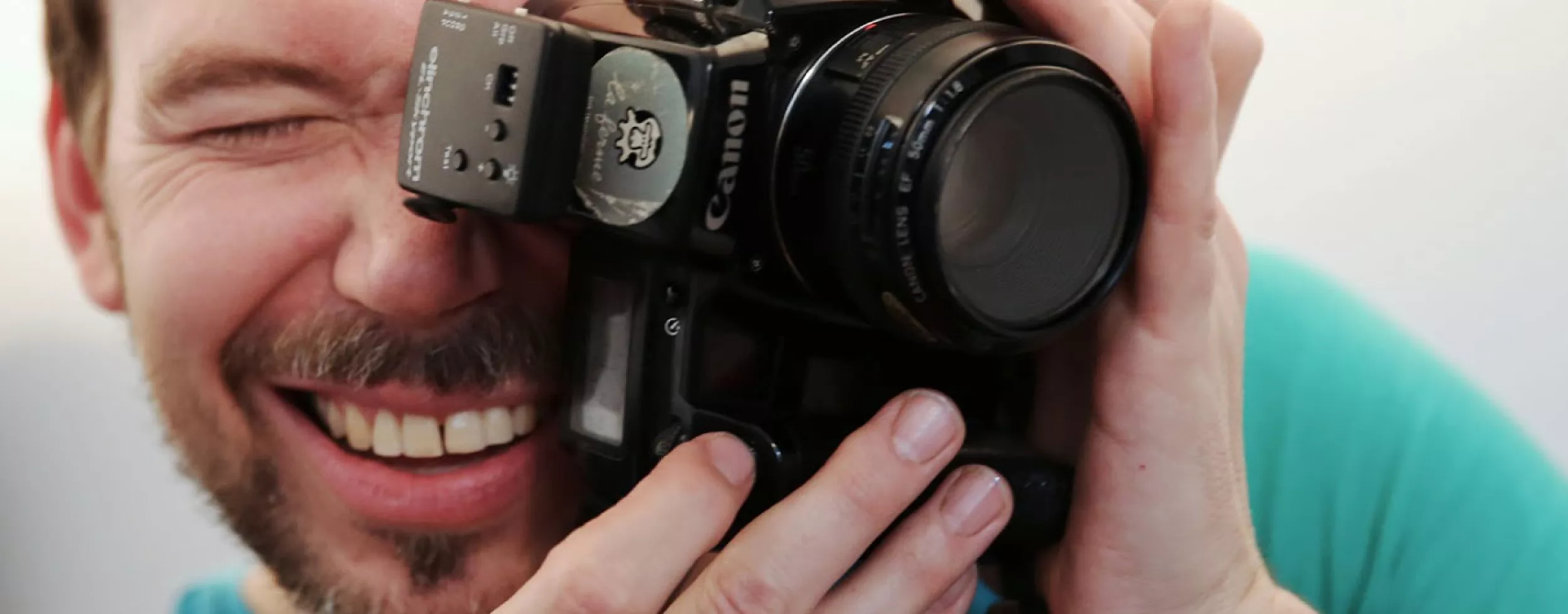 Portraitfoto von Christoph Uiberacker mit Fotoapparat vor Gesicht