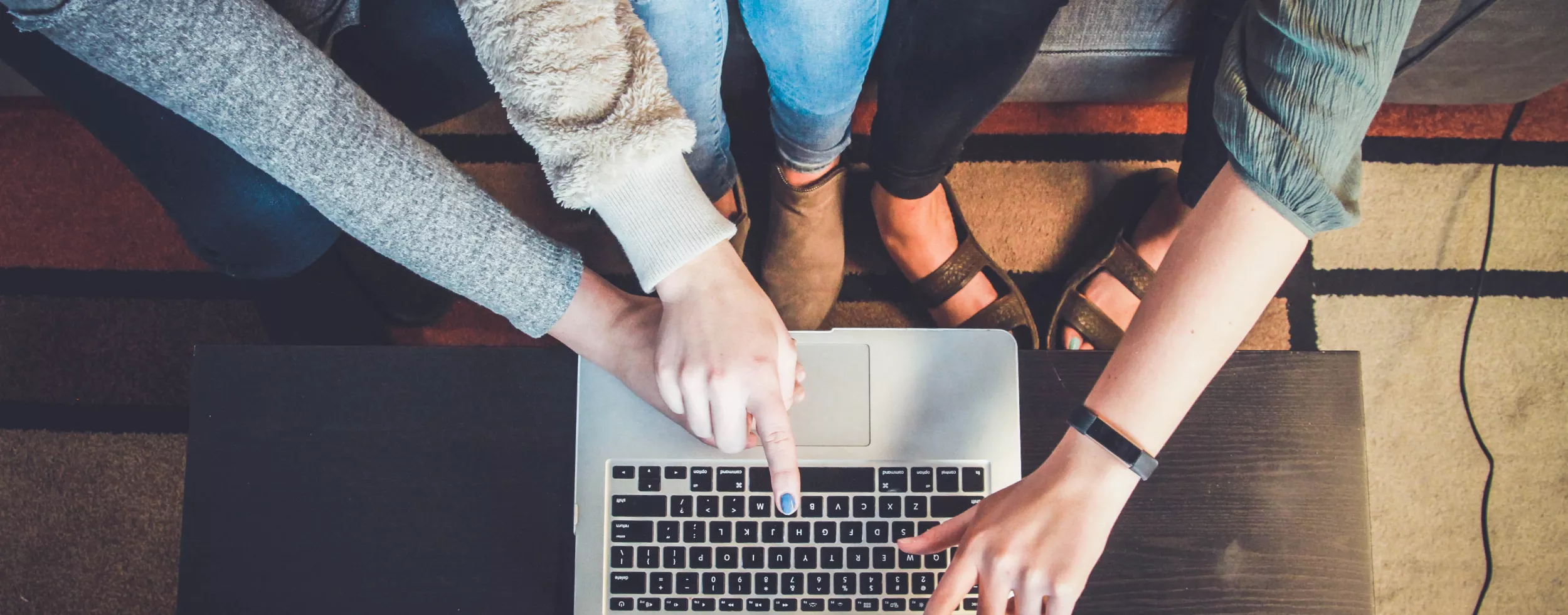 Vier Personen deuten auf einen Laptop